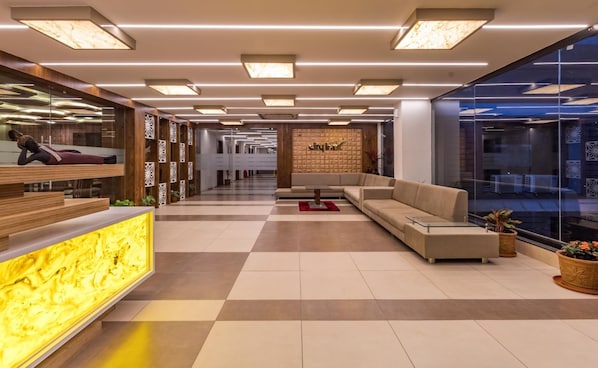 A modern lobby with a reception desk, seating area, and a large window.