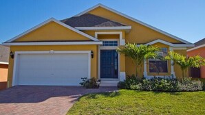 A single-story house with a yellow facade, a white garage door, and a brick pathway leading to the entrance. - Sm218320 - Vizcay - 3 Bed 2 Baths Villa (Davenport)