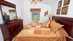 A bedroom with a large bed, a dresser, a television on the dresser, a window with curtains, and framed pictures on the wall. - Sm218320 - Vizcay - 3 Bed 2 Baths Villa (Davenport)