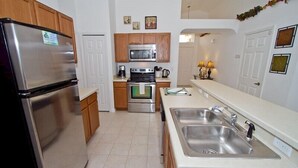 A modern kitchen with stainless steel appliances, wooden cabinets, and a white countertop. - Sm218320 - Vizcay - 3 Bed 2 Baths Villa (Davenport)