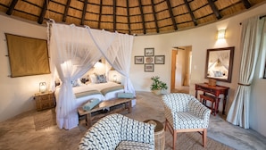 A bedroom with a four-poster bed, bedside lamps, a bedside table, and a large mirror. - Nyala Safari Lodge (Hoedspruit)