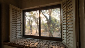 A window with shutters open, revealing a view of trees and a clear sky. - Nyala Safari Lodge (Hoedspruit)