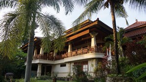A two-story colonial-style building with a balcony, surrounded by lush tropical vegetation. - Gunung Paradis Retreat (Seririt)