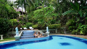 A pool with steps leading into it, surrounded by lush greenery and a stone wall. - Gunung Paradis Retreat (Seririt)