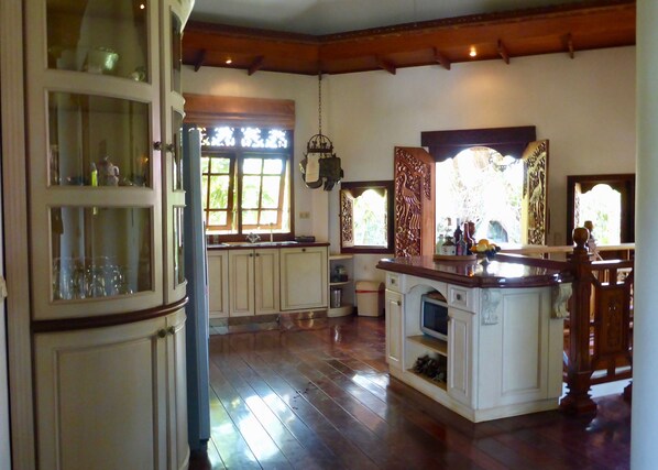Una cocina amplia con pisos de madera, armarios blancos y una isla central.