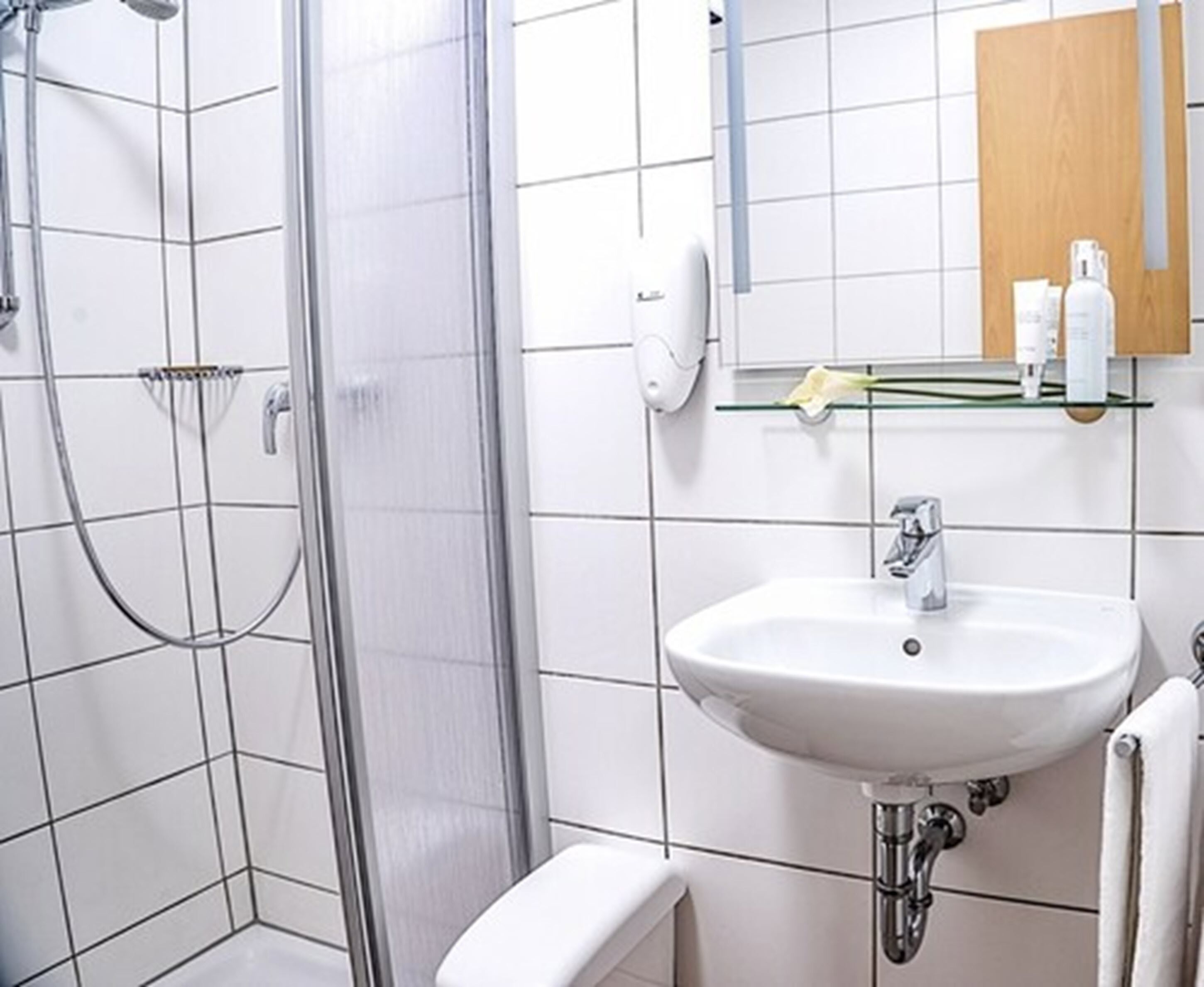 A bathroom with a shower, a sink, and a mirror.