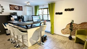 Et moderne køkken med barområde, spisebord og en grøn stol.