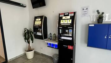 A reception area with two ATMs, a potted plant, a blue cabinet, and a mounted television.