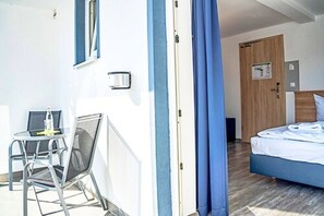 A room with a bed, a small table with chairs, a window, and a door. - Sunny Hotel (Aiterhofen)