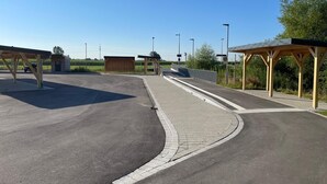En parkeringsplads med overdækkede læskure og en belagt sti.