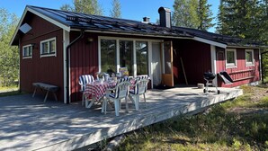 A red cabin with a covered patio, outdoor seating, and a barbecue area. - Holiday Home Fjätervålen Fjätstigen (Sarna)
