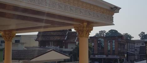 Un espacio al aire libre techado con columnas, una bandera y un estacionamiento.