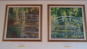 Two framed paintings of a bridge over water, with labels underneath.