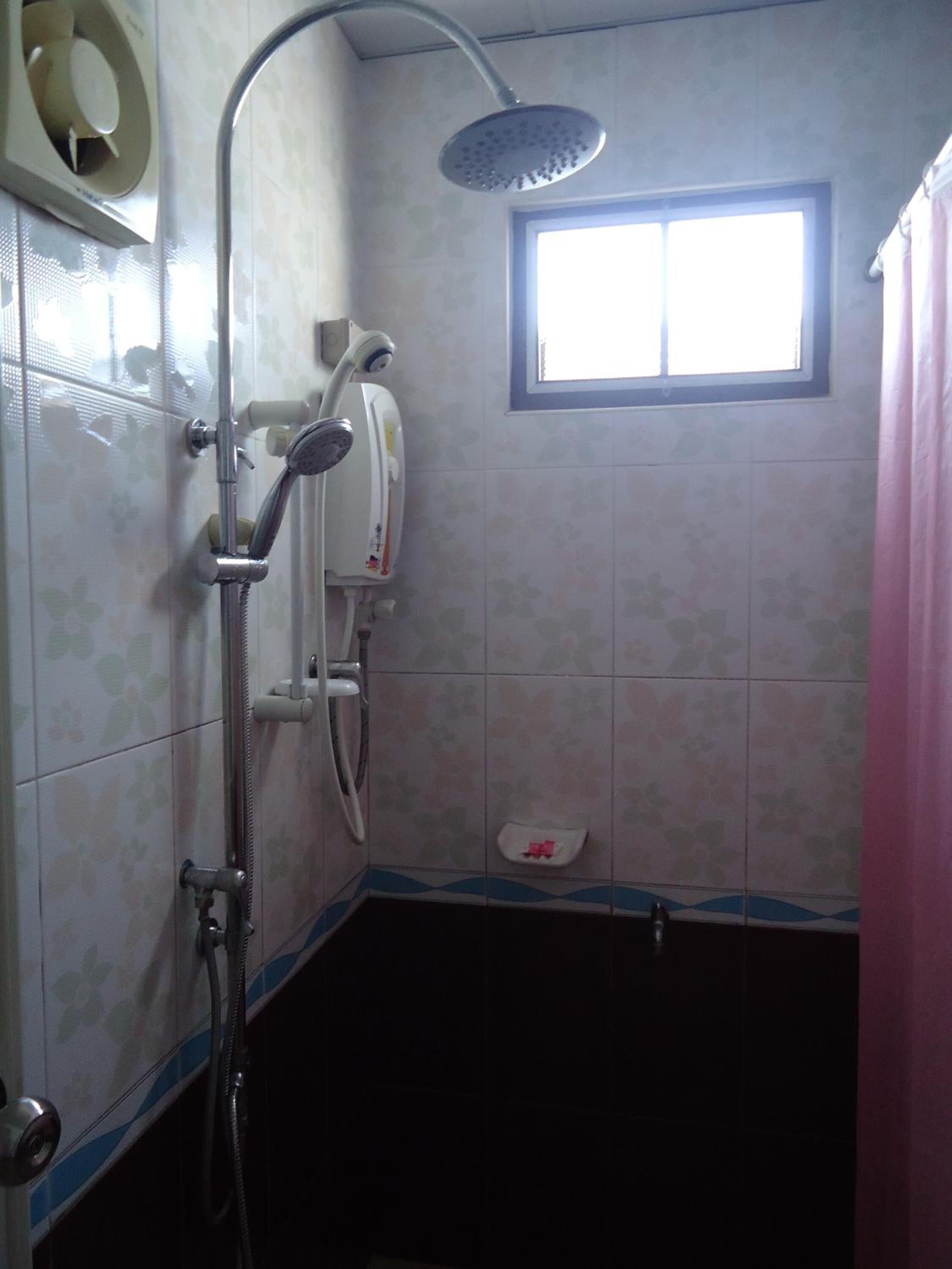 Un baño con ducha, ventana e inodoro.