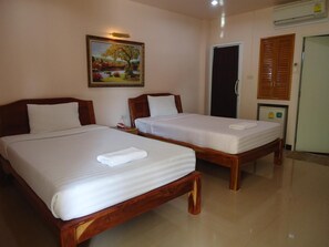 Two wooden beds with white linens and a painting of a landscape above them.