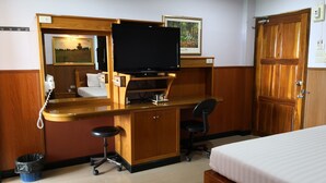 A hotel room with a wooden desk, a television, a bed, and a small bathroom area. - Phadaeng Hotel (Ubon Ratchathani)