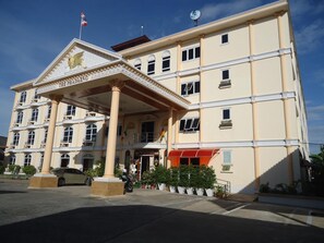 A multi-story hotel with a prominent entrance, a flag, and a satellite dish.