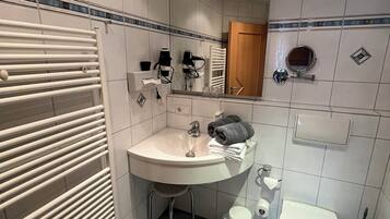 Ein Badezimmer mit Waschbecken, Spiegel, Handtuchhalter und Toilette.