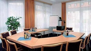 Uma sala de conferências com uma mesa grande, cadeiras, um quadro branco e um projetor.