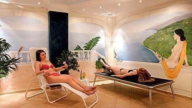Um quarto de spa com uma cadeira reclinável, uma mesa de massagem e um mural de uma mulher em um penhasco.