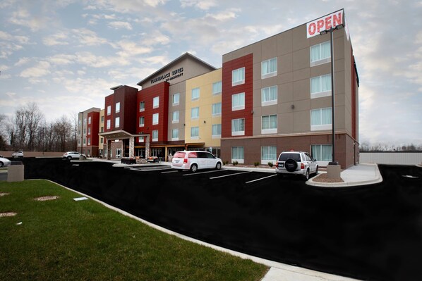 Een meerlaags hotel met een 'Marriott' bord, een parkeerplaats en een 'OPEN' bord.