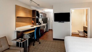 A hotel room with a bed, a desk with a chair, a kitchenette, a TV, and a bathroom. - TownePlace Suites by Marriott Louisville Airport (Louisville)