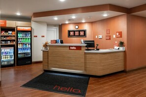 Een hotel receptie met een receptiebalie, een klok en automaten.