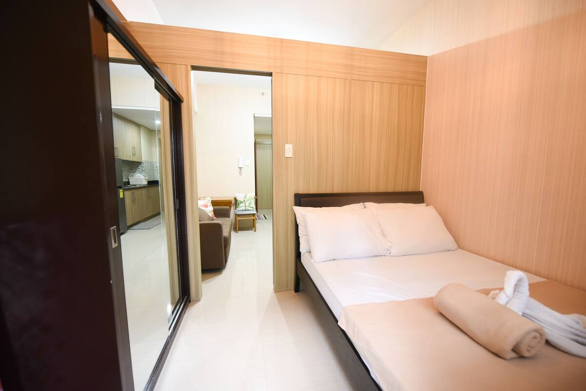 Quarto de hotel com cama, uma mesinha e uma cadeira.