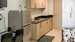 Cozinha compacta com armários de madeira, geladeira, pia e ventilador de teto.