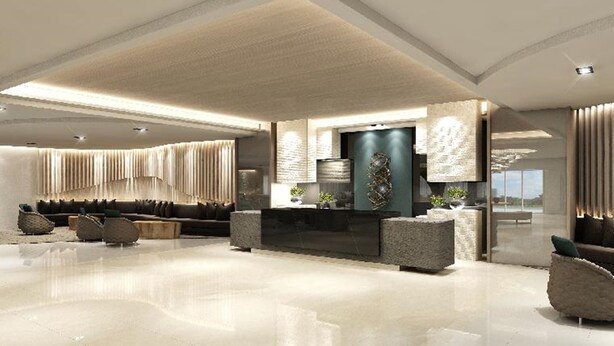 Um hall amplo com design moderno, apresentando uma área de estar central com sofás e um balcão de recepção grande e de cor escura.