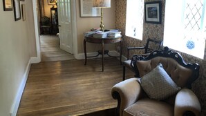 A room with a wooden floor, a sofa, a table with papers, a lamp, and a chair. - Carrick's At Castle Farm (Dereham)
