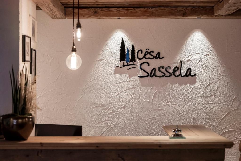 A reception desk with a logo above it, a hanging light fixture, and a potted plant to the left.