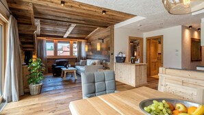 A cozy cabin interior with wooden beams, a dining area, and a kitchen. - Residence Cesa Sassela (Ortisei)