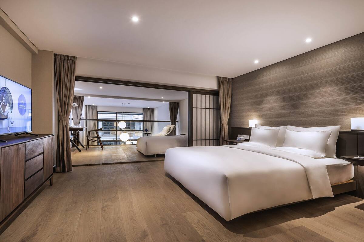 Una habitación de hotel moderna con una cama grande, televisión y vistas a la ciudad.