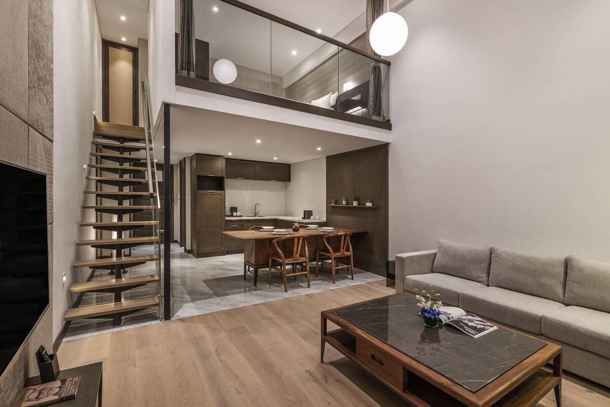 Un interior moderno con una escalera, un comedor, un sofá y una mesa de centro.