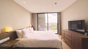 A hotel room with a large bed, a TV, a wooden dresser, and a balcony with a view of the city. - Novotel Suites Shanghai Hongqiao Hotel (Shanghai)
