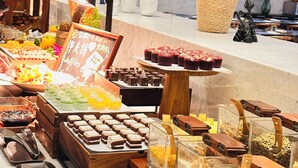 Un buffet proposant une variété de plats, notamment des pâtisseries, des fruits et des boissons.