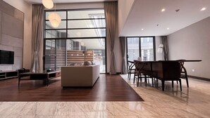 Un salon spacieux avec une grande fenêtre, un canapé, une table à manger et un téléviseur.
