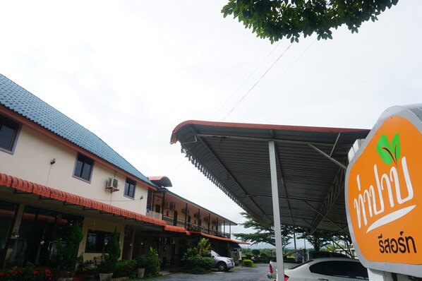 A building with a covered entrance and a sign with a green leaf symbol. - Thapap Resort (Trang)