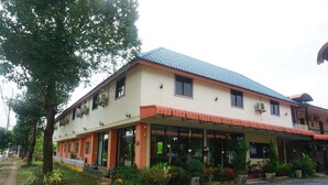 A two-story building with a tiled roof, a covered porch, and a garden with potted plants and flowers. - Thapap Resort (Trang)