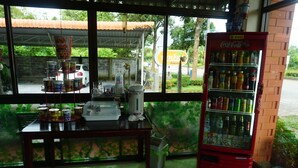 A room with a vending machine, a table with food containers, and a view of the outside. - Thapap Resort (Trang)