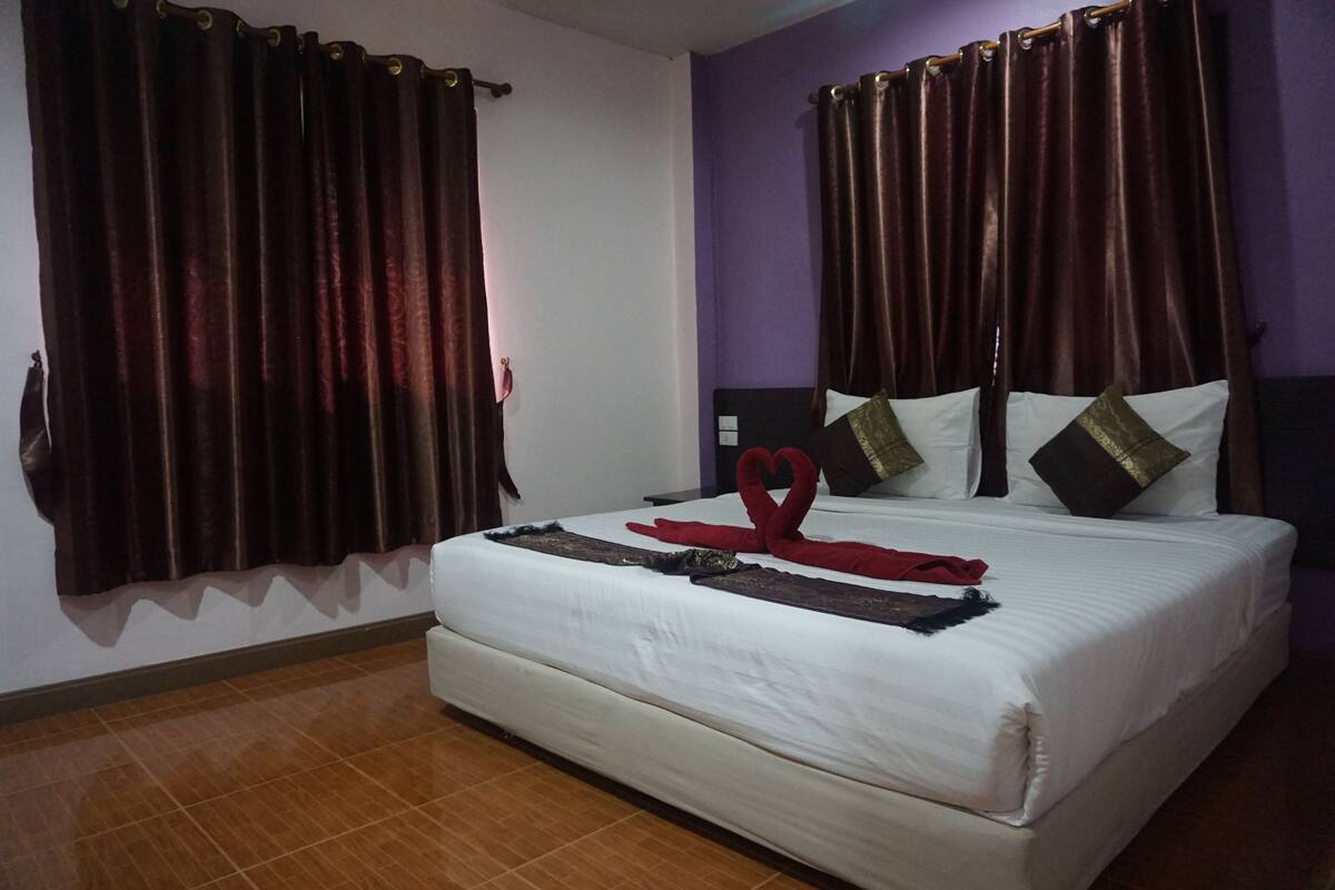 A hotel room with a large bed, dark curtains, and a simple, clean design.