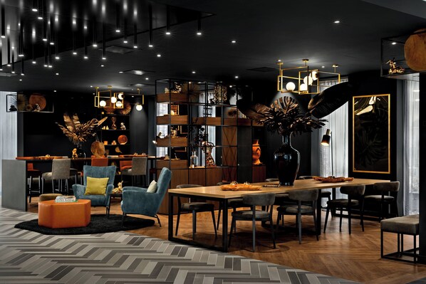A modern interior with a dining area, seating, and a bookshelf. - Renaissance Amsterdam Schiphol Airport Hotel (Aalsmeer)