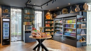 Un espacio comercial moderno con una mesa de exhibición central, estantes repletos de diversos productos y una sección refrigerada.