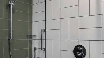 A shower with a handheld showerhead and a wall-mounted control panel.