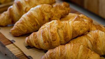 A wooden board with several golden-brown croissants arranged on it.
