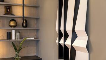 A modern interior with a wooden shelf holding decorative items, a vase with a plant, and a geometric wall art piece.