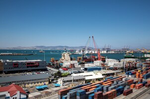 Un puerto con contenedores de envío, grúas y un barco atracado en el Terminal de Cruceros de Ciudad del Cabo.