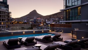 Uma área de piscina no terraço, com espreguiçadeiras e vista para uma montanha.