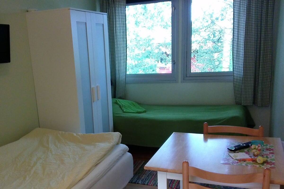 A room with a bed, a desk with a chair, a wardrobe, and a window with curtains.